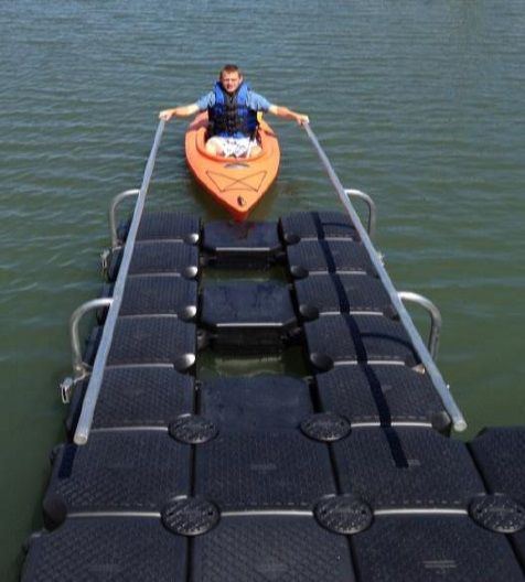 A man in an orange kayak is sitting on a dock