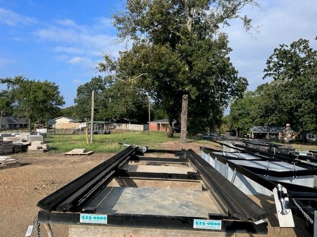 A row of trailers are sitting in a dirt field with trees in the background.