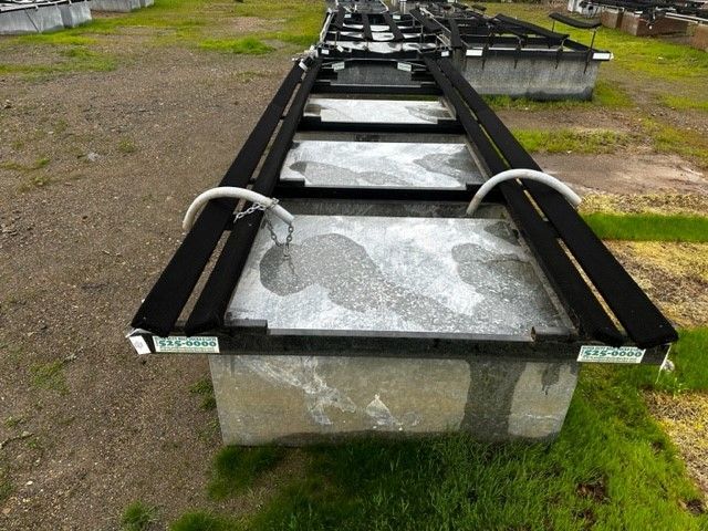 A large metal container is sitting in a grassy field