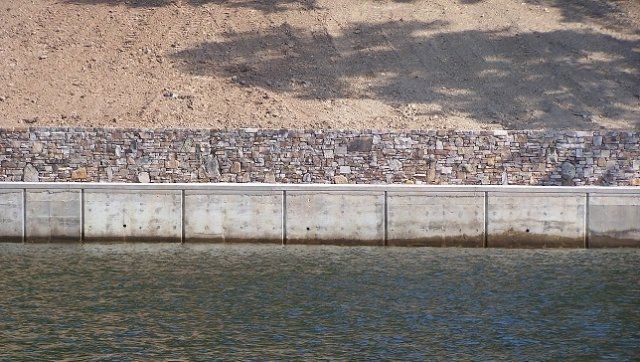 A concrete wall surrounds a body of water.