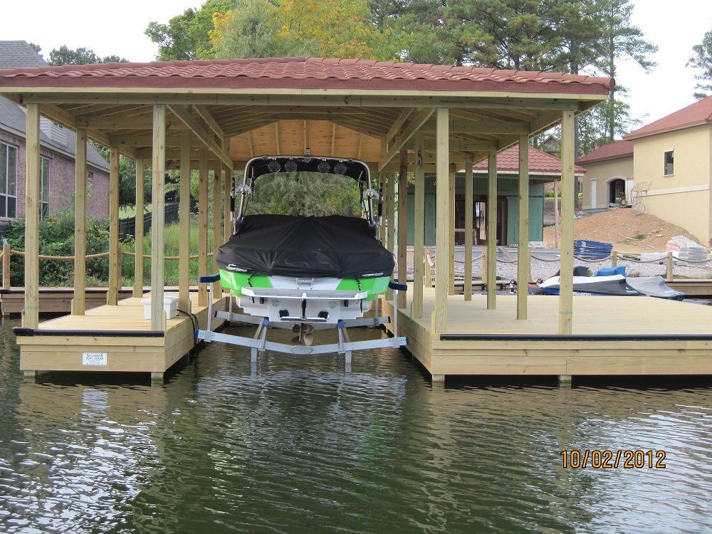 A boat is sitting under a covered dock on a lake.