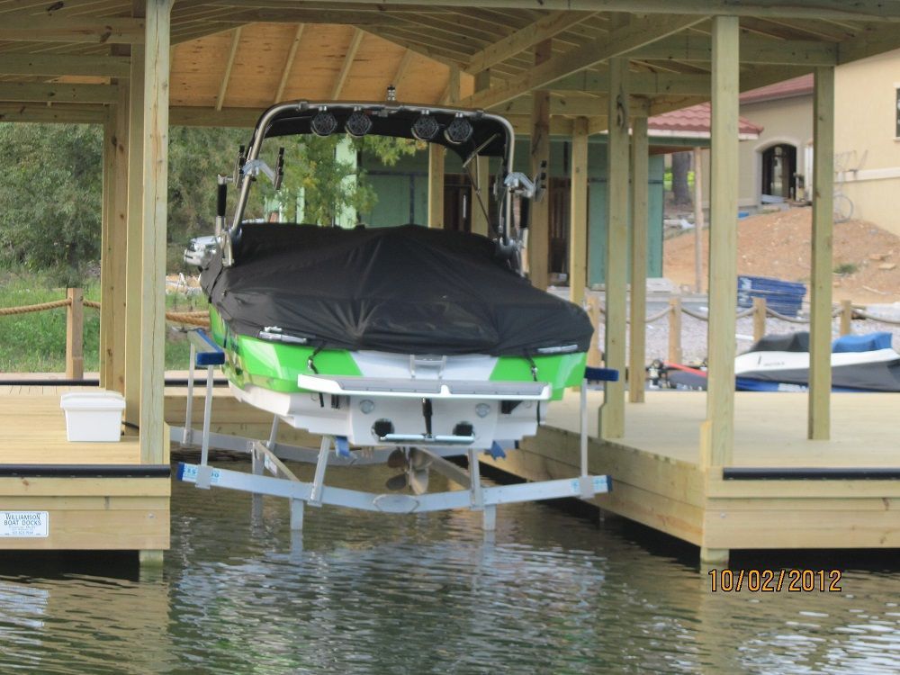 A green and white boat is sitting on a lift in a dock.
