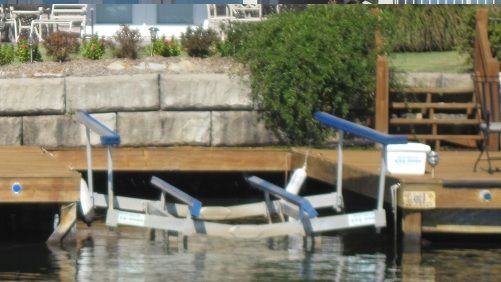 A boat lift is attached to a wooden dock in the water