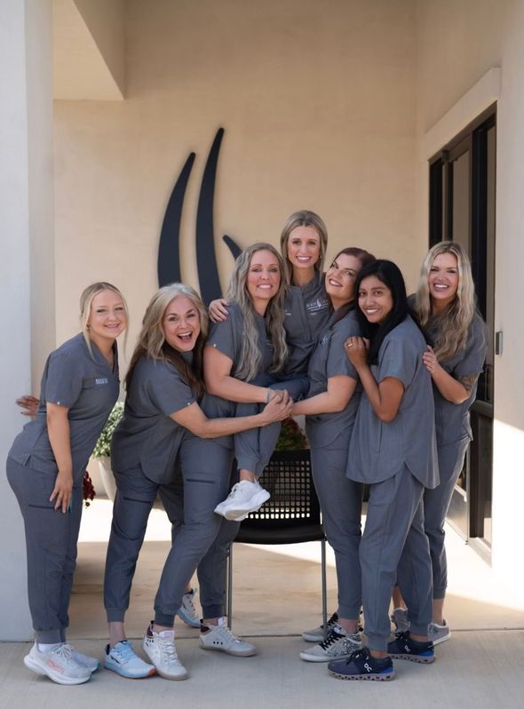 Two women in purple scrubs are posing for a picture.