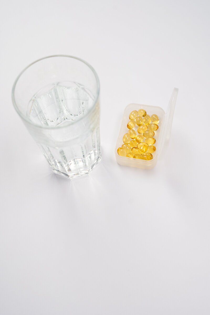 A glass of water and a box of pills on a table.