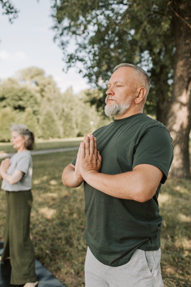 A man and a woman are practicing yoga in a park.