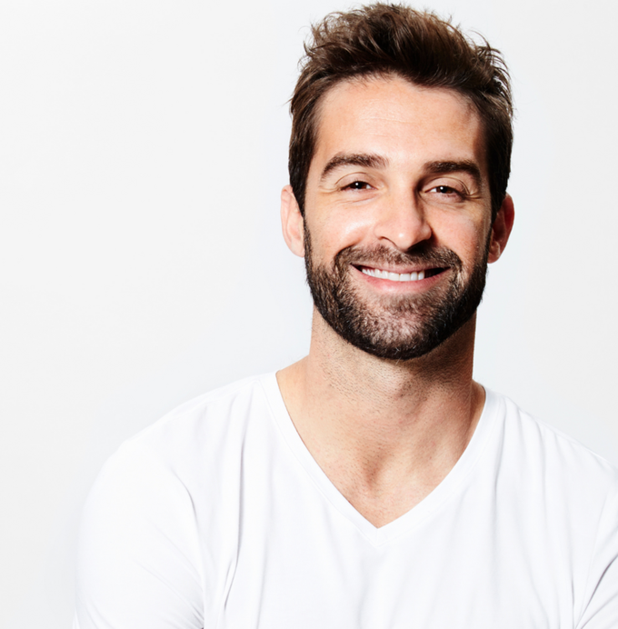 A man with a beard is wearing a white shirt and smiling