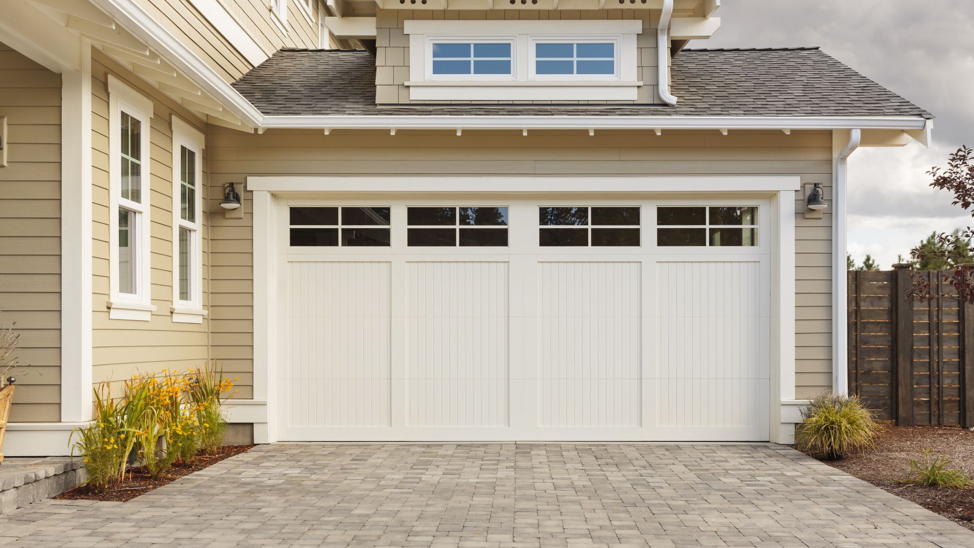 A house with a white garage door and a brick driveway.