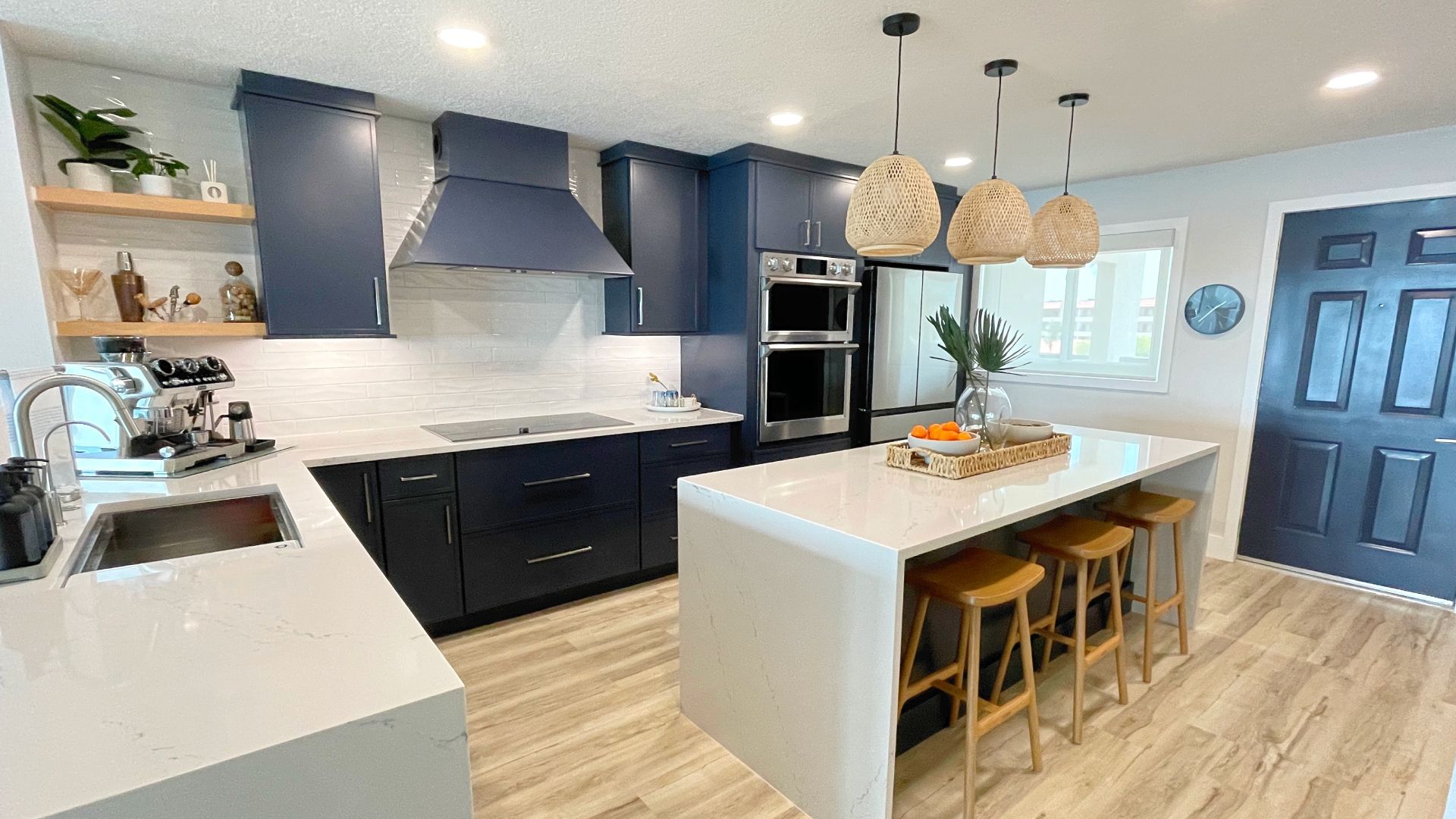 A kitchen with blue cabinets , white counter tops , stools and a large island.