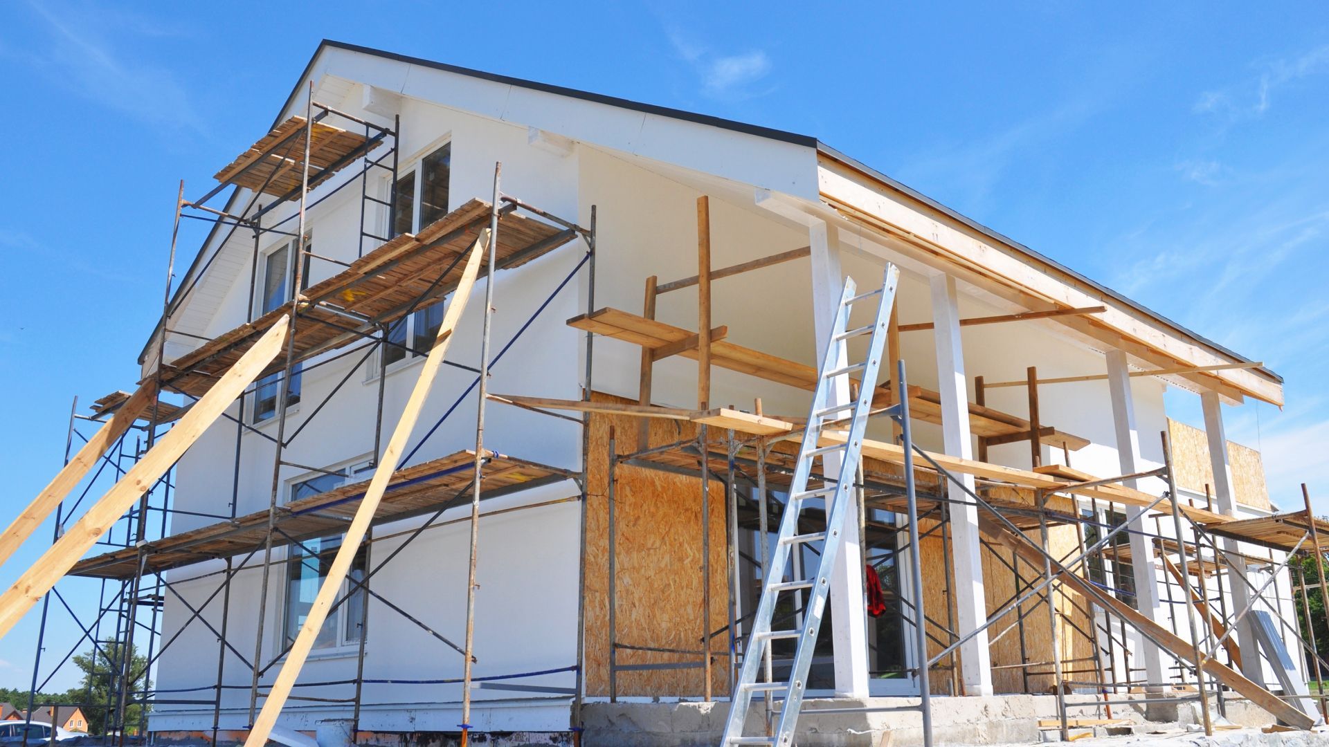 A house is being built with scaffolding and a ladder.
