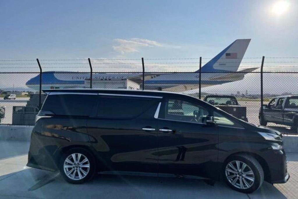 A black van is parked in front of an air force one plane