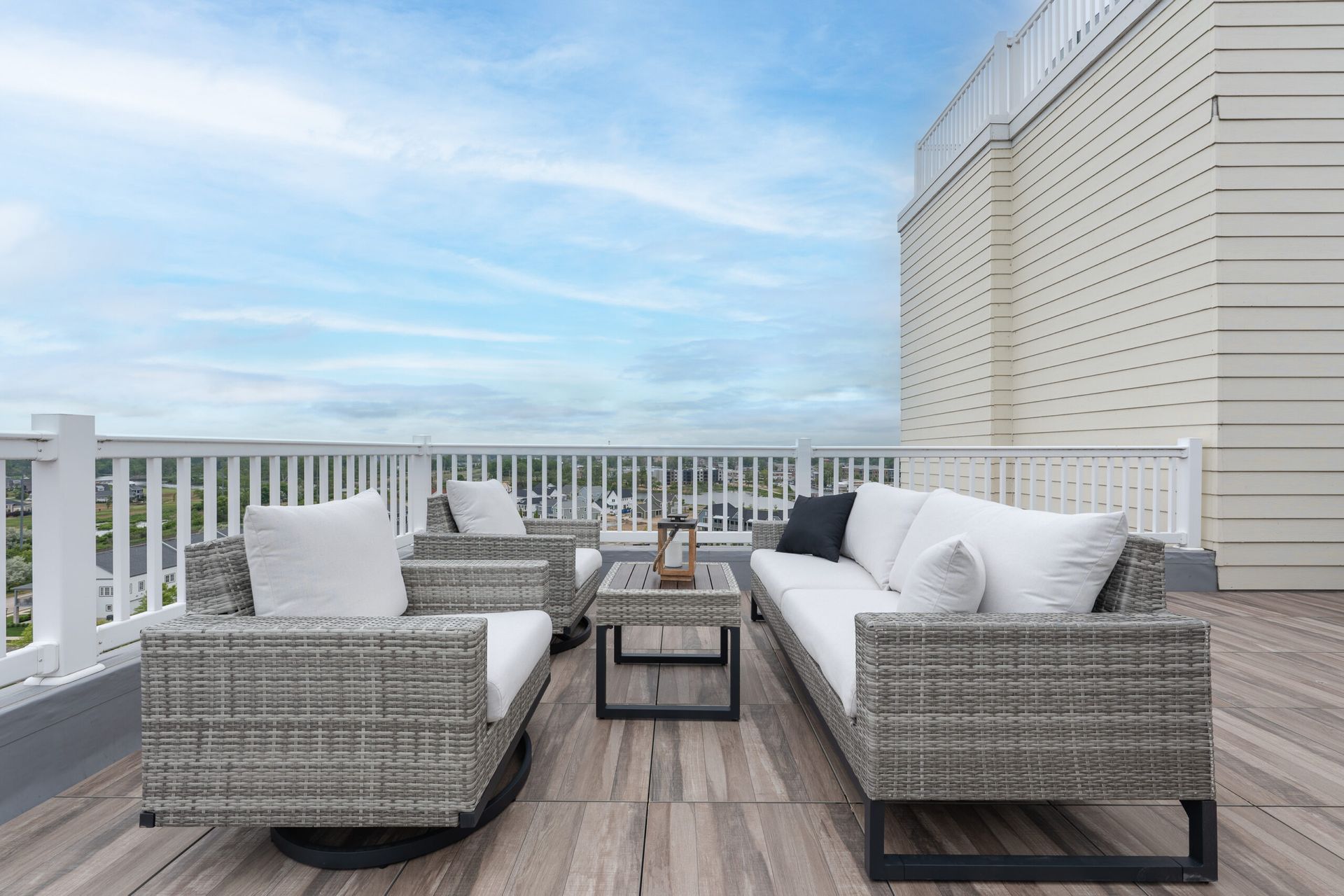 A rooftop deck with a couch , chairs , and a table.