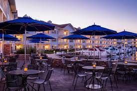 A patio with tables and chairs and blue umbrellas in front of a building.