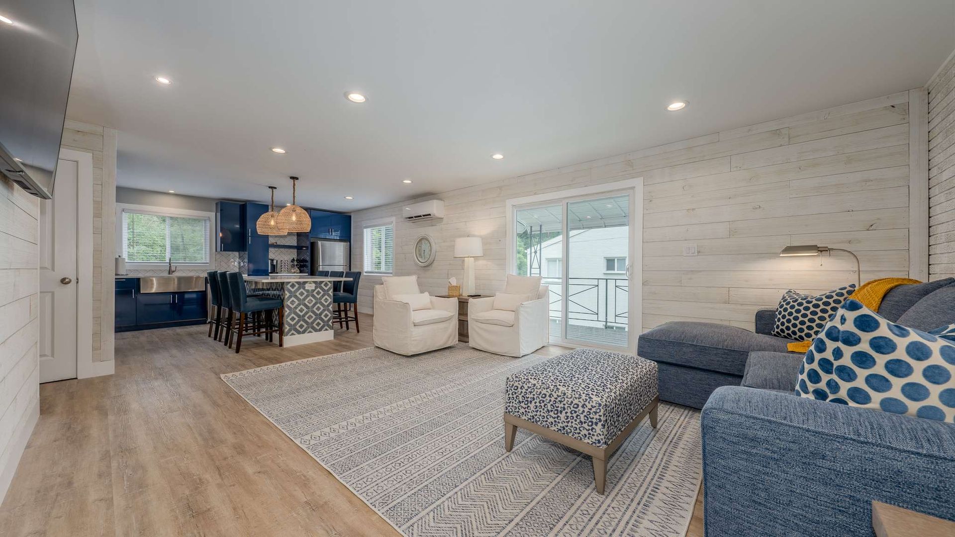 A living room with a couch , chairs , ottoman and rug.