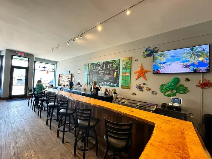 A restaurant with a long bar and a television on the wall.