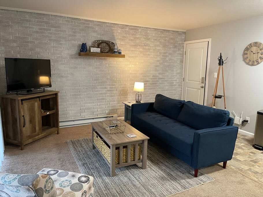 A living room with a blue couch , coffee table , and television.