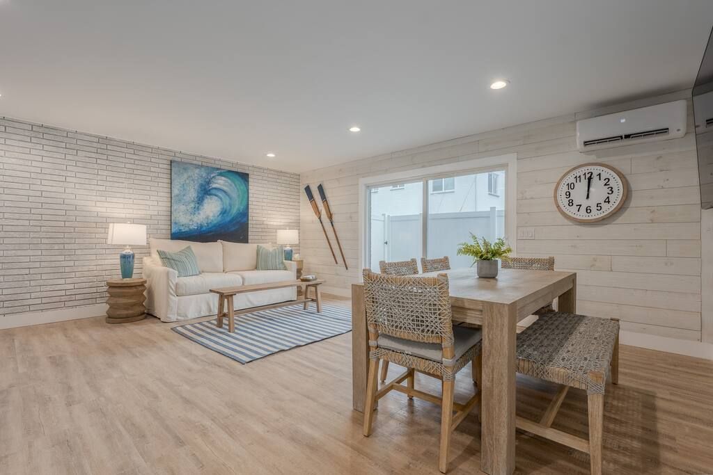 A living room with a table and chairs and a clock on the wall.