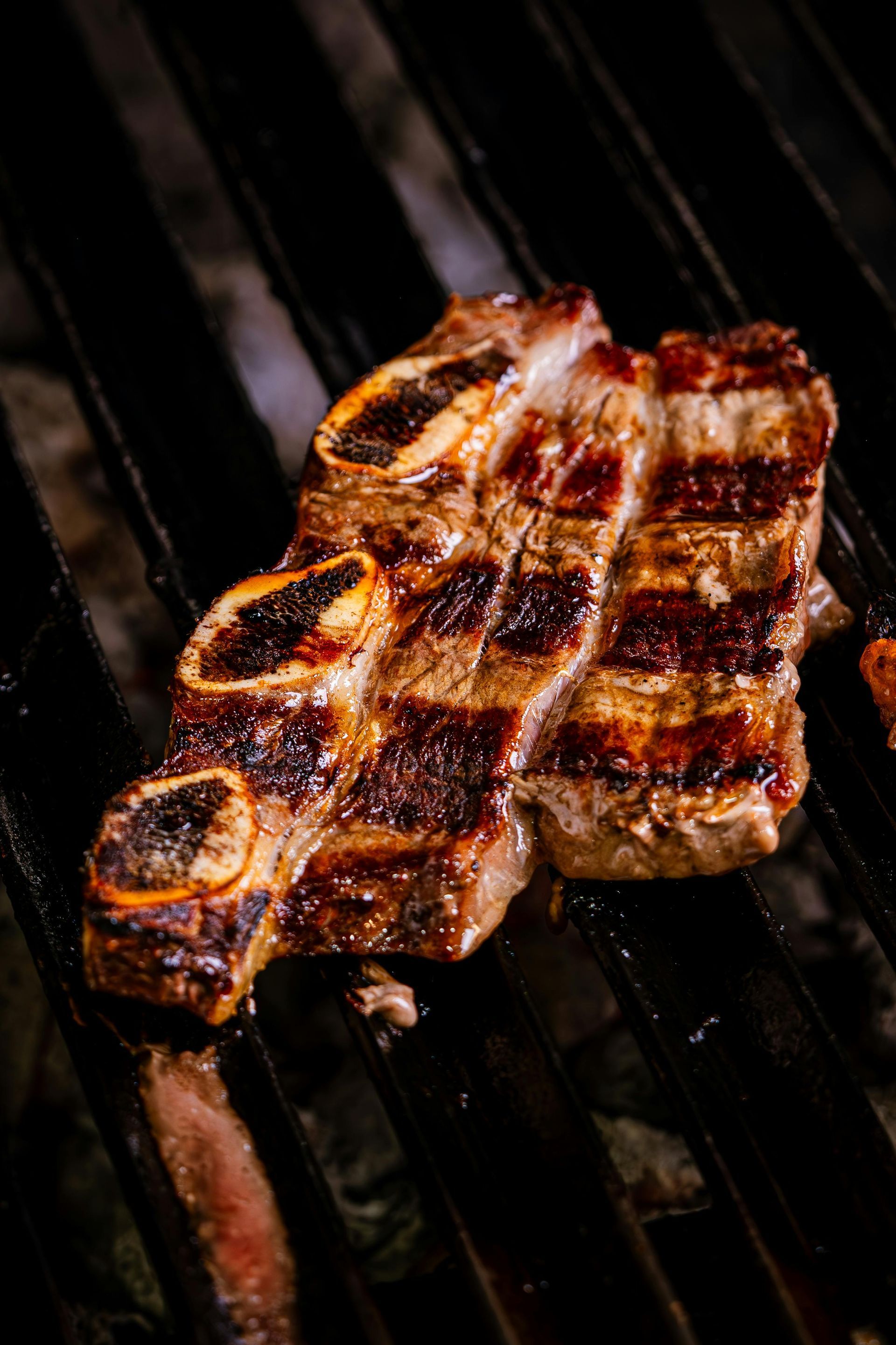 Grilled short rib on a dark grill, showing grill marks.