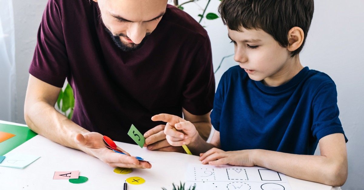 A father and son duo are playing a game during therapy at home. They're learning and having fun together.