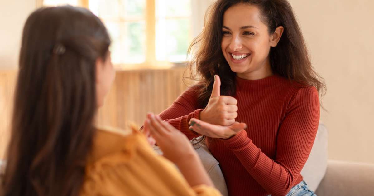 A mother and daughter are hanging out together. Both are using sign language.