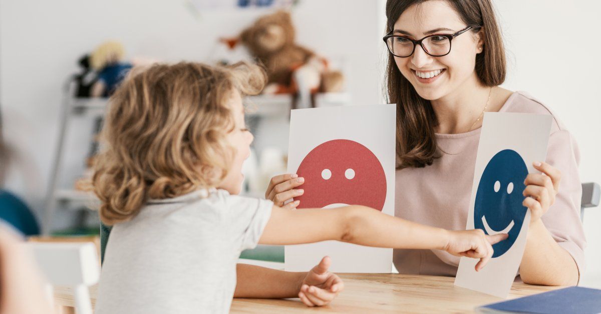 A psychologist and child use pictures to communicate during a therapy session.