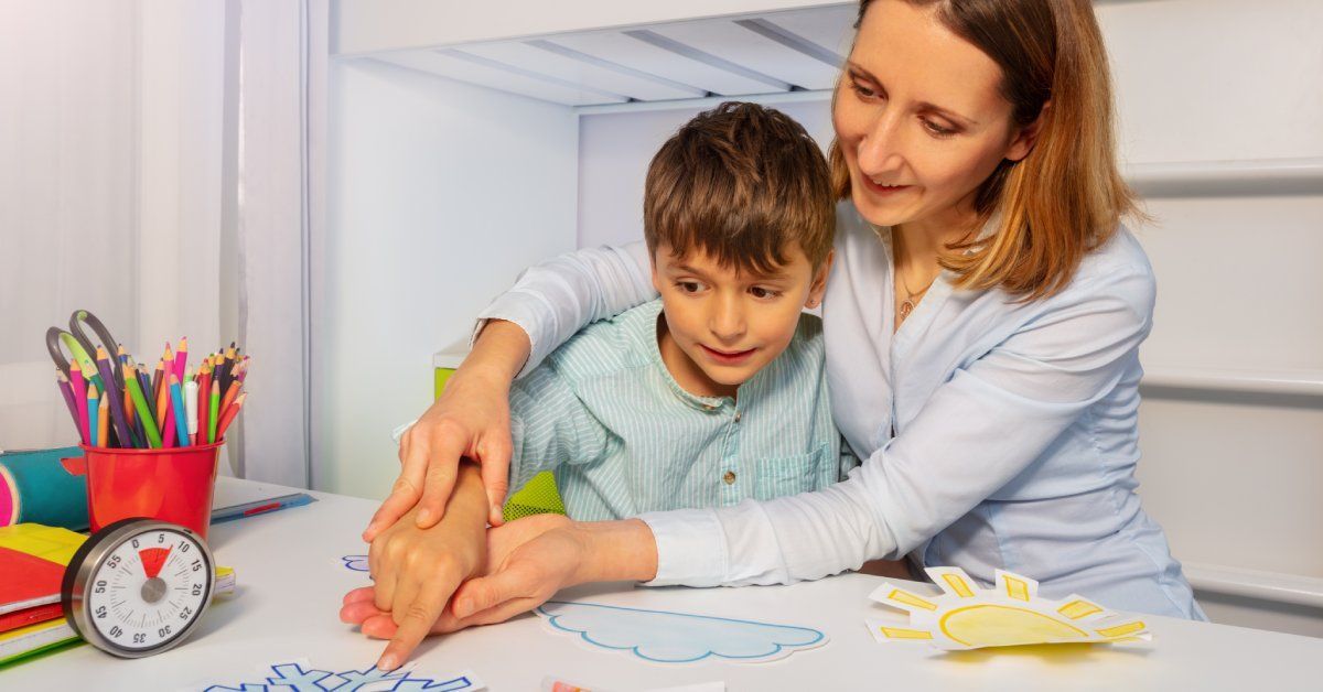 A boy and his teacher. The teacher uses her hand to impart instructions.