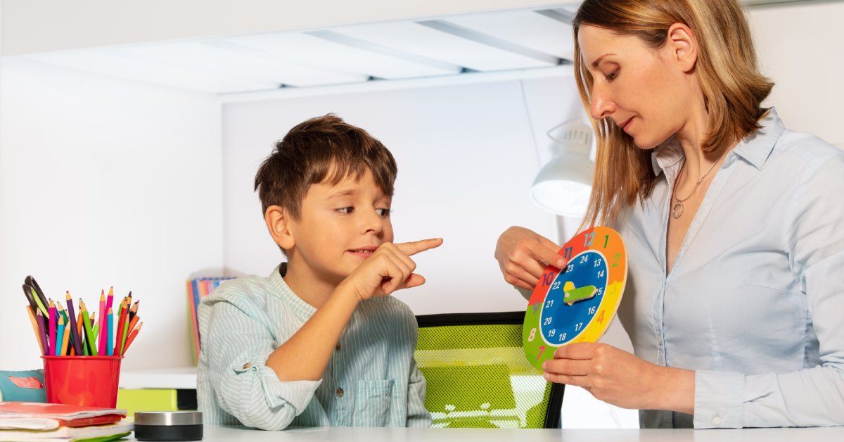 A young boy is pointing to a colorful paper clock that an adult is holding to teach him how to tell time.