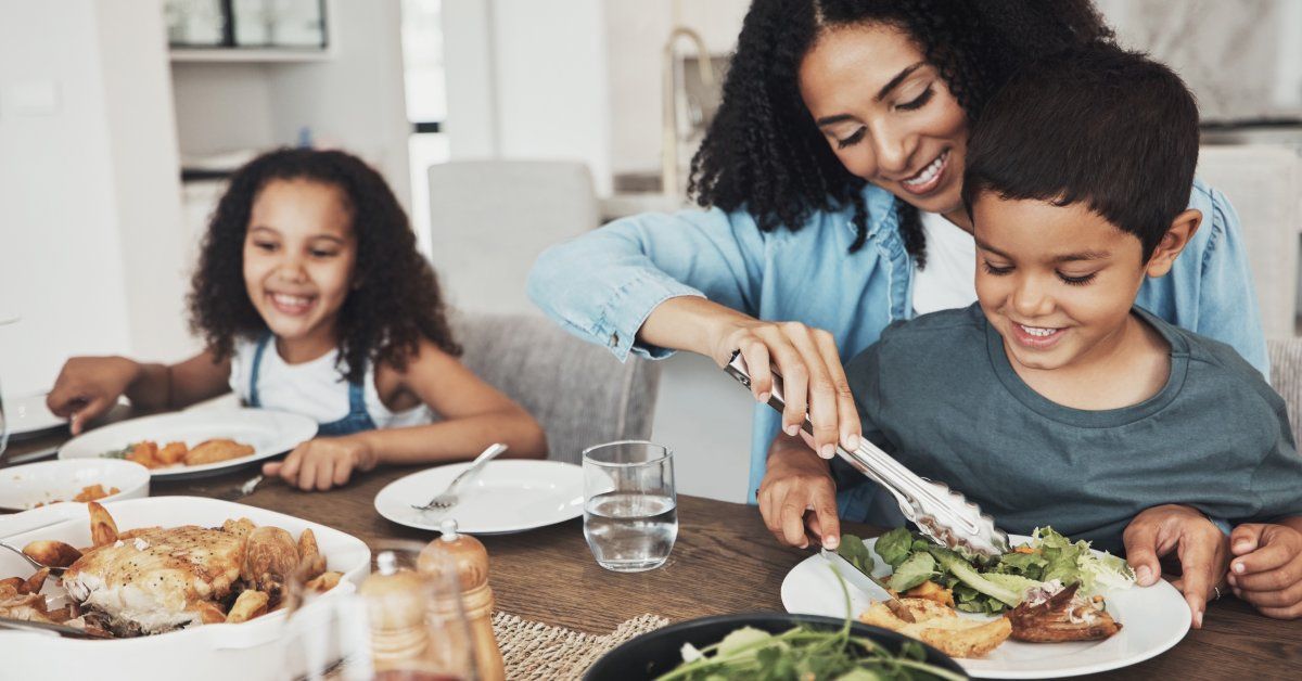 A mother and her two children, a boy and girl, are sitting at the table eating.