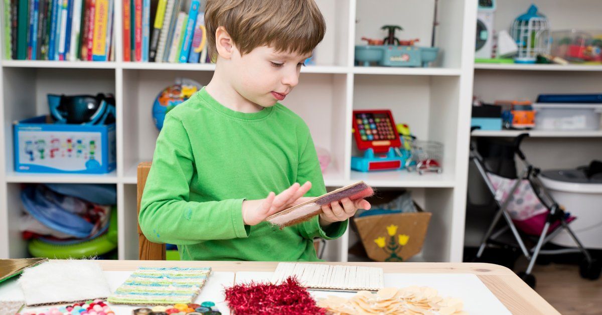 A little boy wearing a green long-sleeved shirt searches through a deck of cards.
