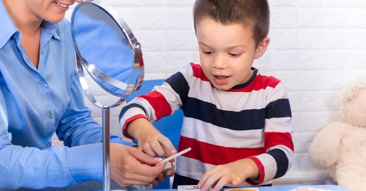 A boy with autism uses his picture exchange communication system to communicate with his ABA therapist during therapy.