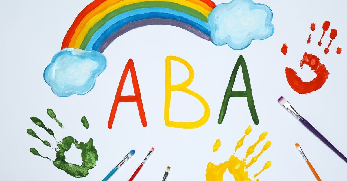 A rainbow arches over the letters “ABA” as paintbrushes and handprints cover the page.