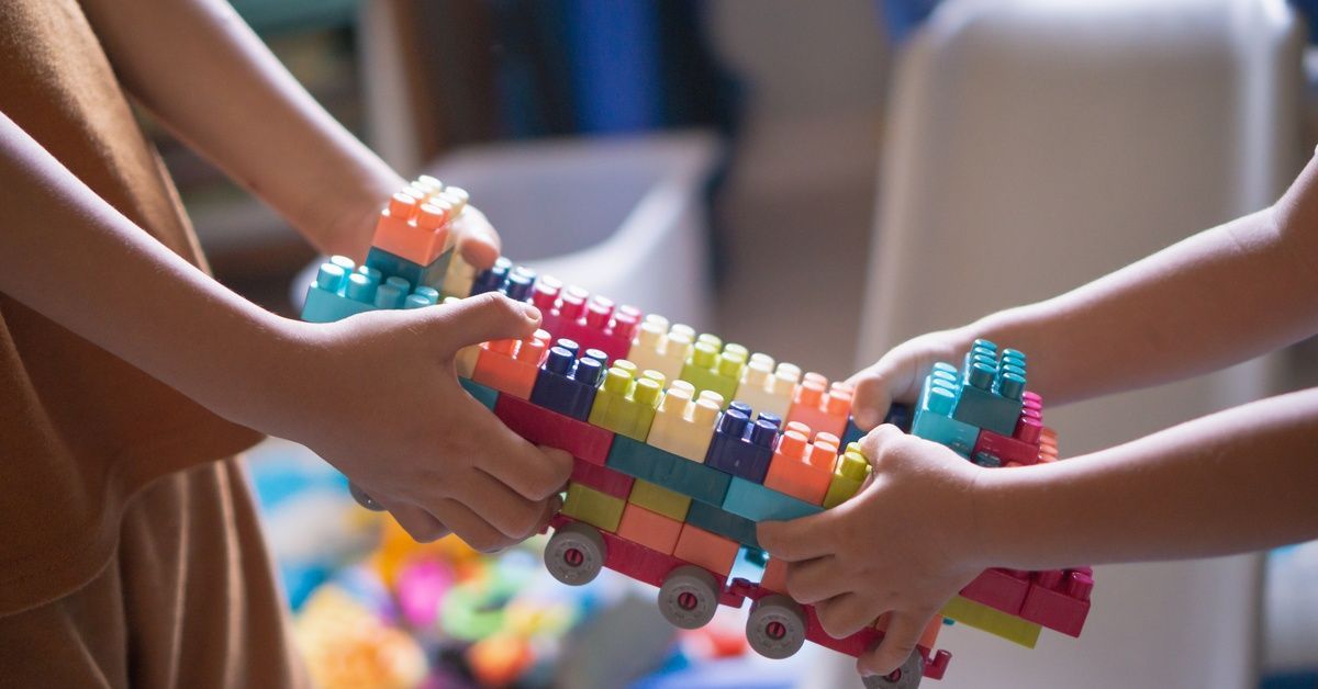 Two children both pull a colorful block airplane toward them during playtime.