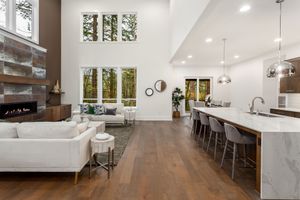 Bright open-plan living room and kitchen with white sofas, wood floors, and long island seating