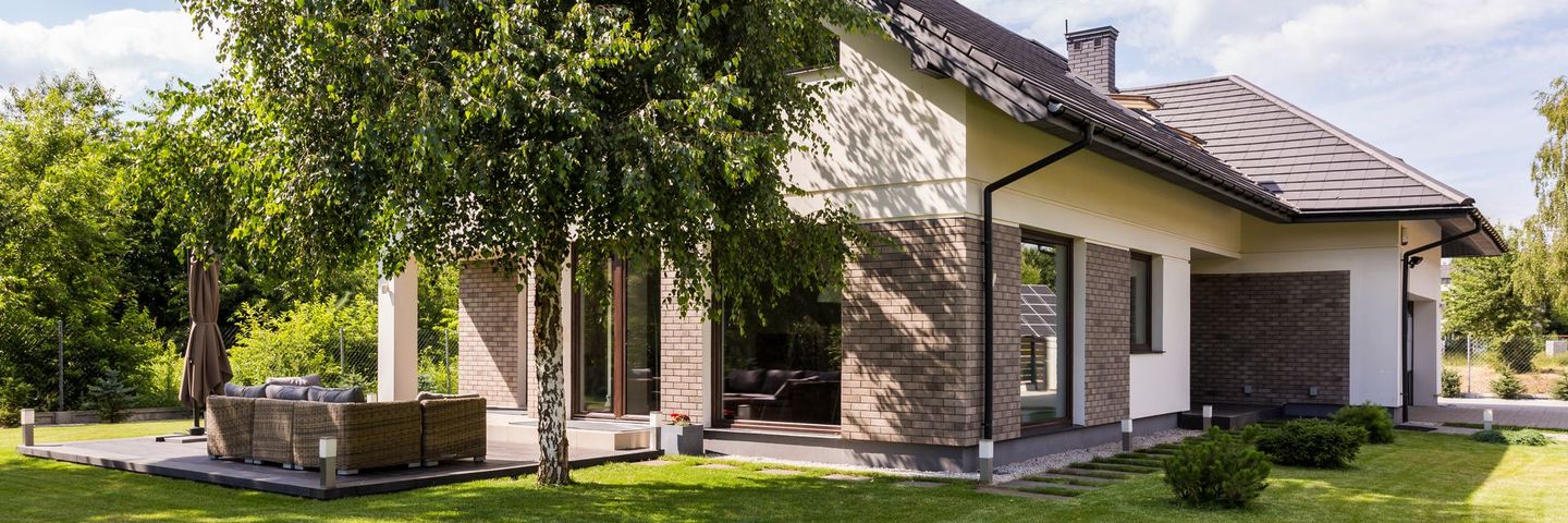 Une grande maison avec une pelouse verdoyante et des arbres devant.