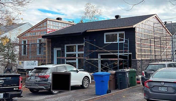 Une maison en construction avec des voitures garées devant.