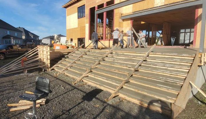 Une terrasse en bois est en cours de construction devant une maison en construction.