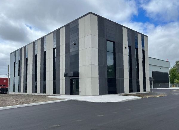 Un grand bâtiment avec de nombreuses fenêtres se trouve au bord de la route.