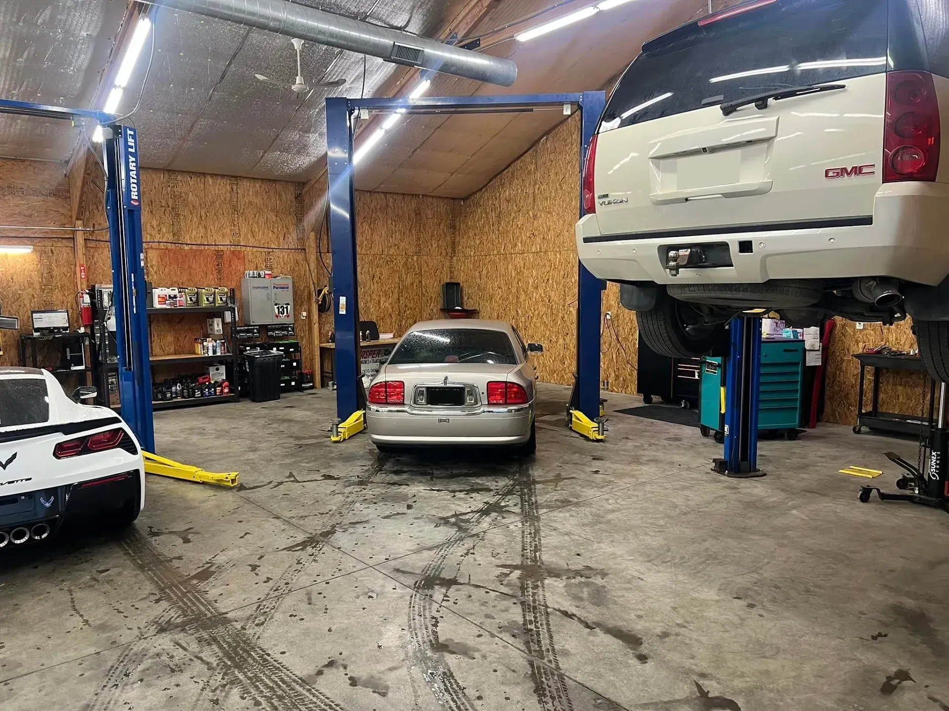 Garage with Car on a Lift, Silver Sedan, and White SUV | Auto Care Center