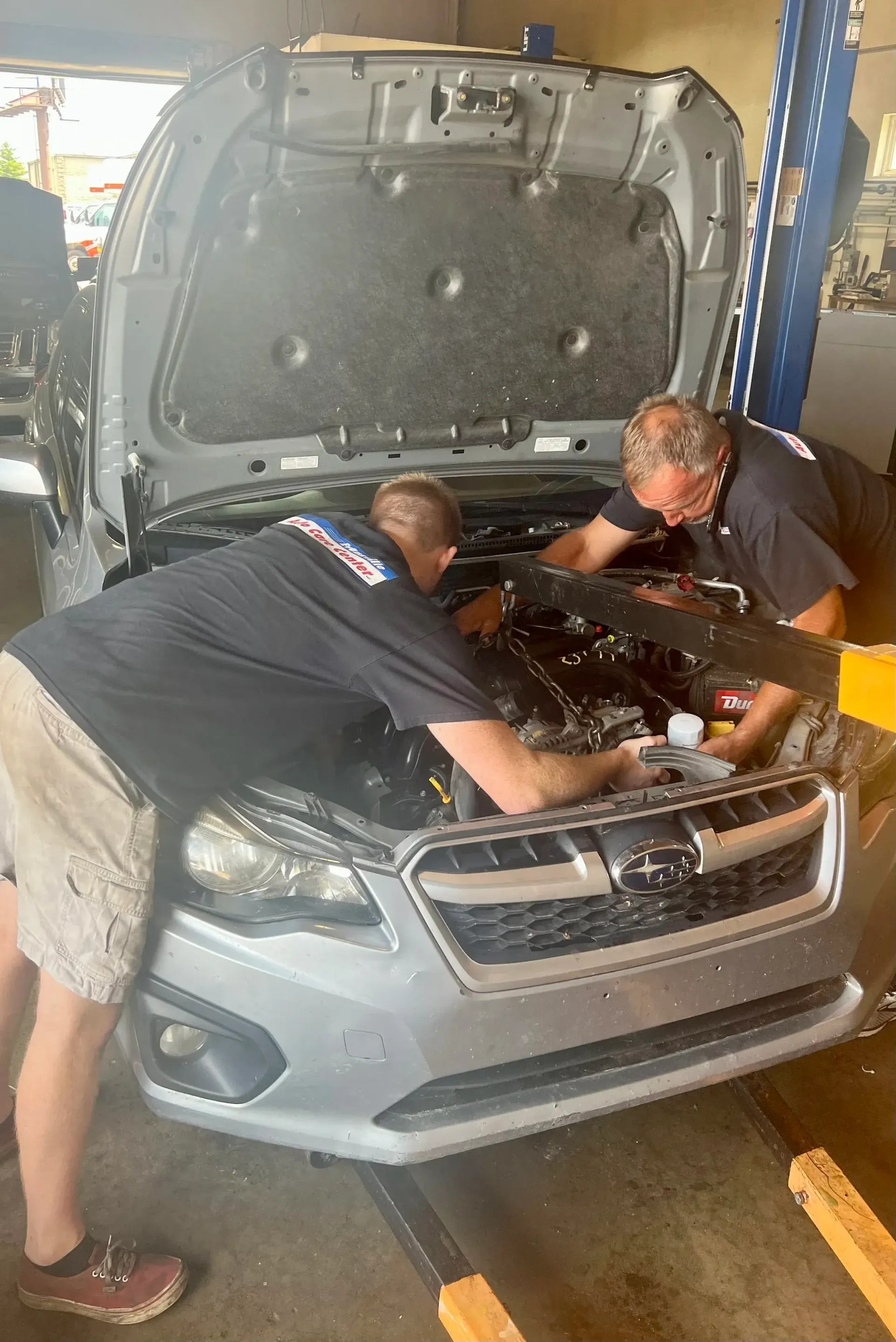 Two Mechanics Working on a Car Engine with Hood Open | Auto Care Center