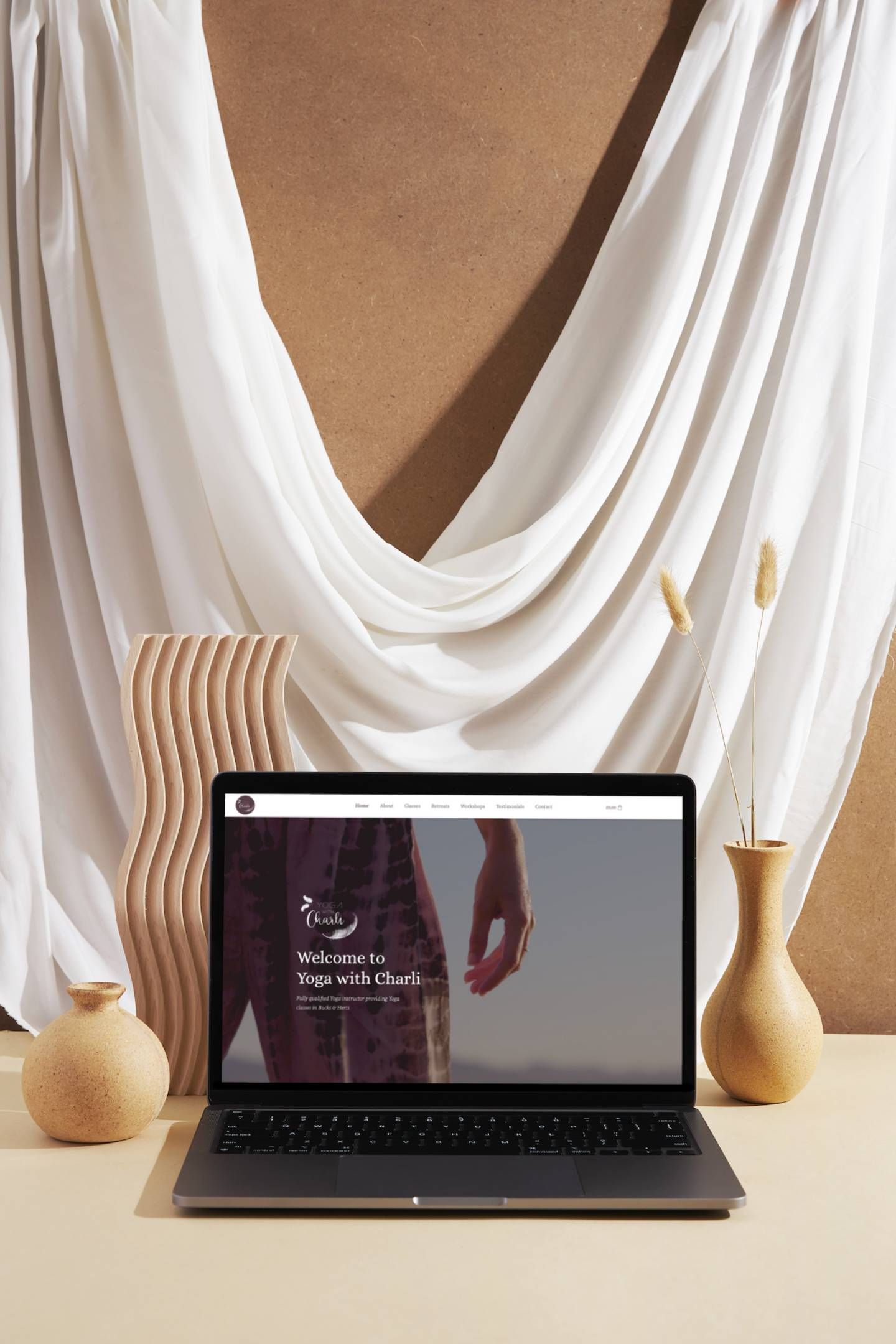 A laptop computer is sitting on a table next to vases.