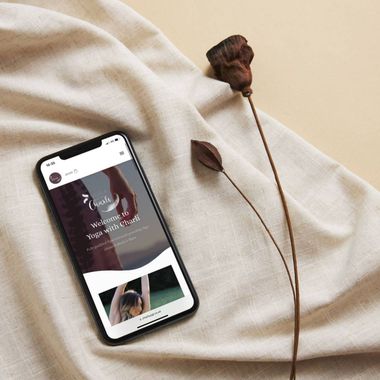 A cell phone is sitting on a piece of cloth next to a flower.