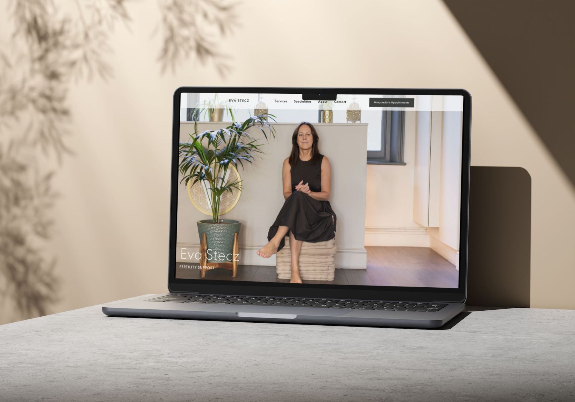 A laptop computer is open to a video of a woman sitting on a stool.