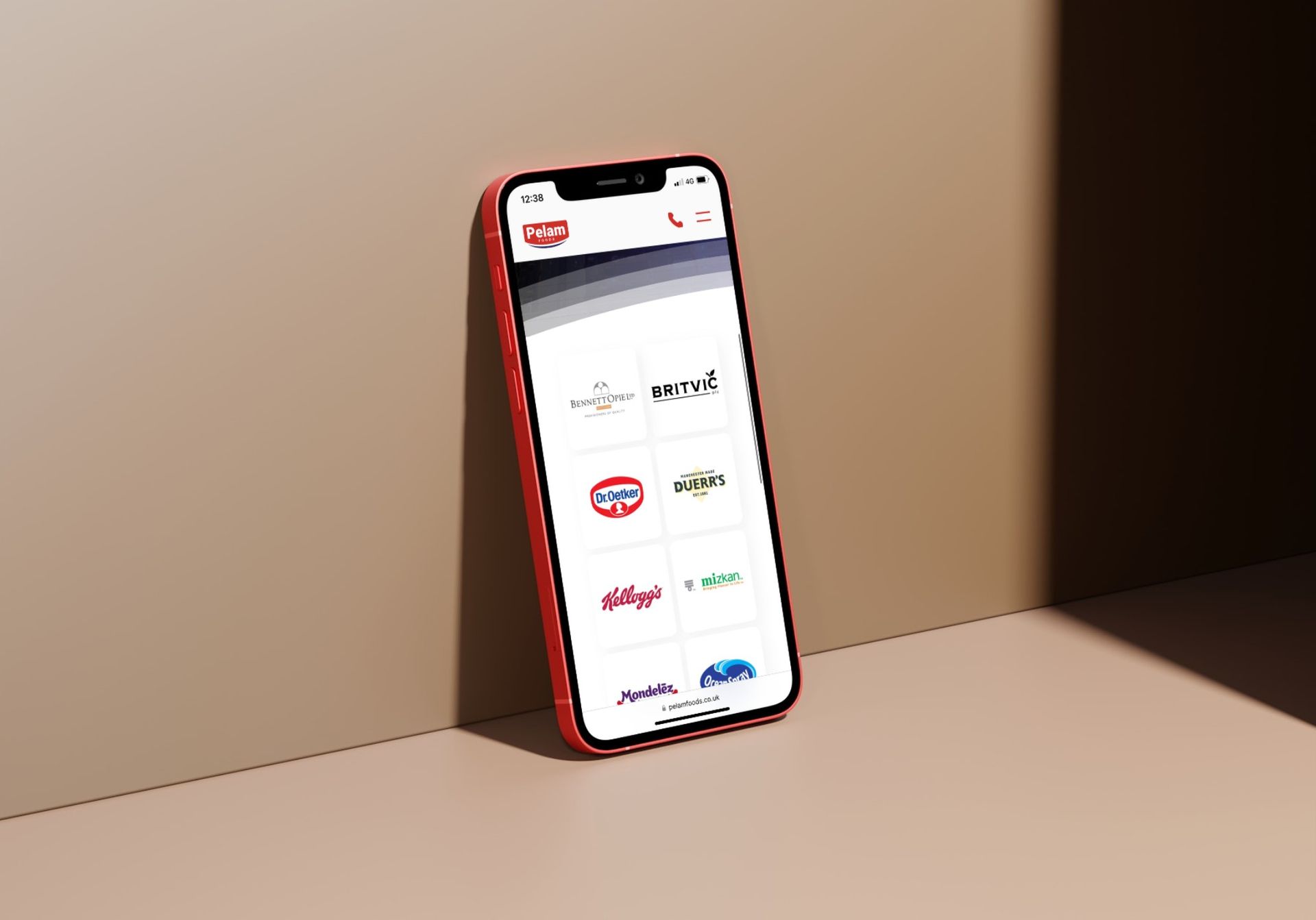 A red cell phone is sitting on a table next to a wall.