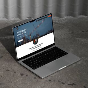 A laptop with a website on the screen is sitting on a concrete surface.