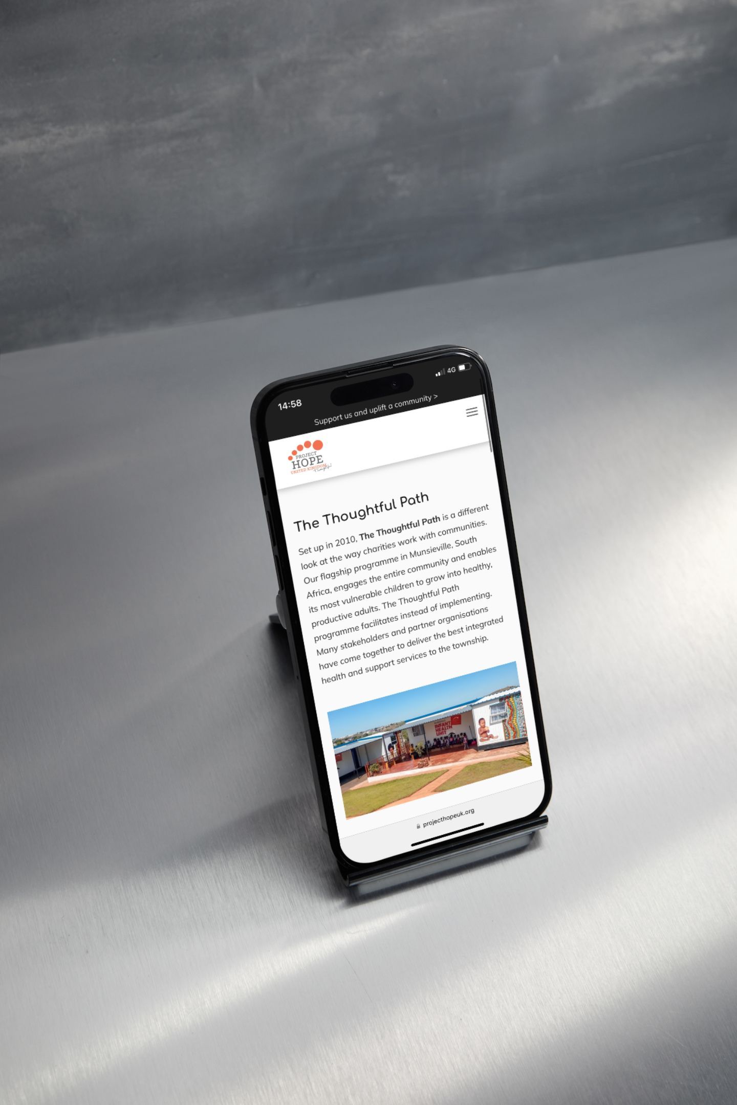 A cell phone is sitting on a stand on a table.