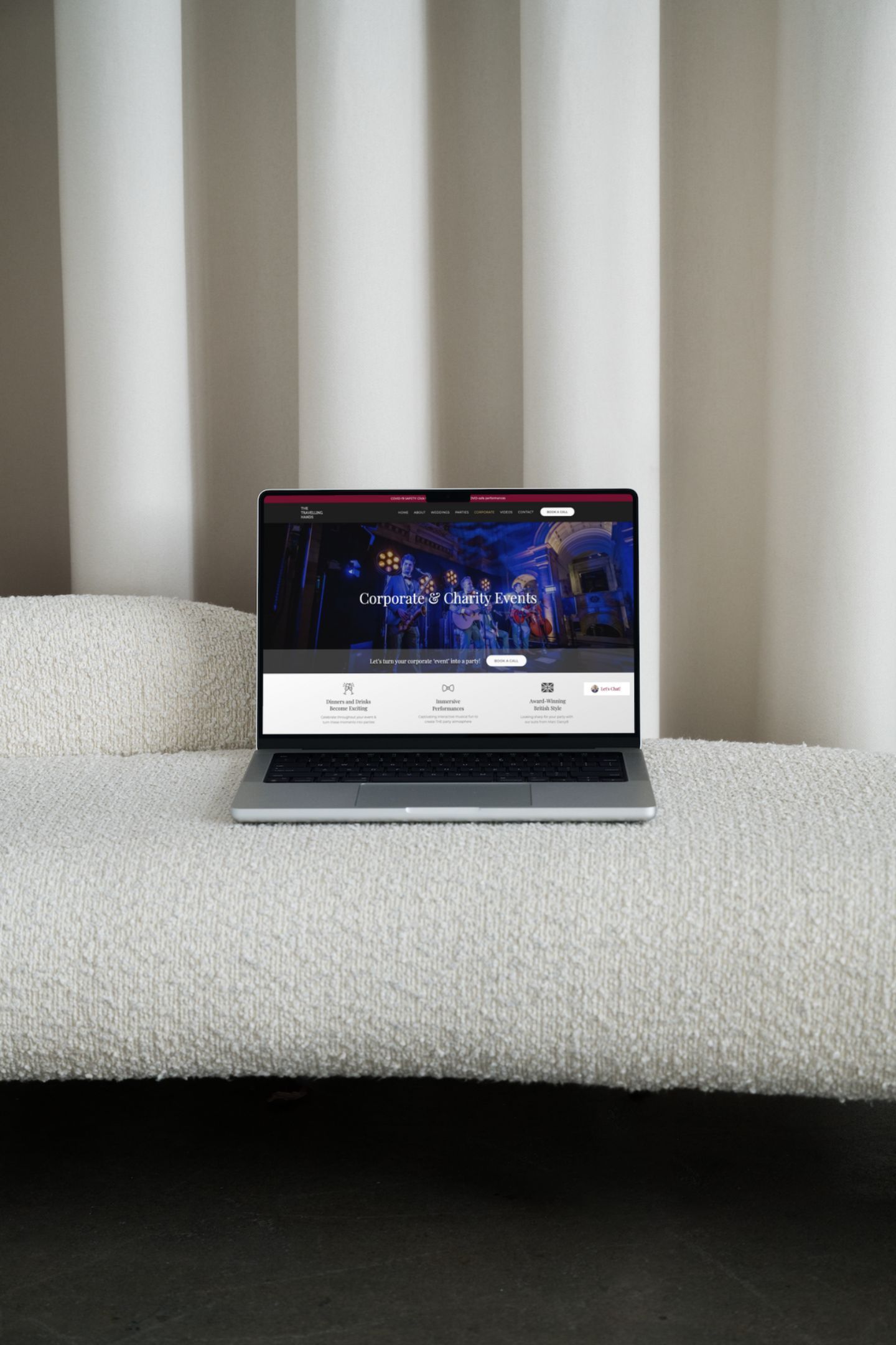 A laptop computer is sitting on a bed next to a window.