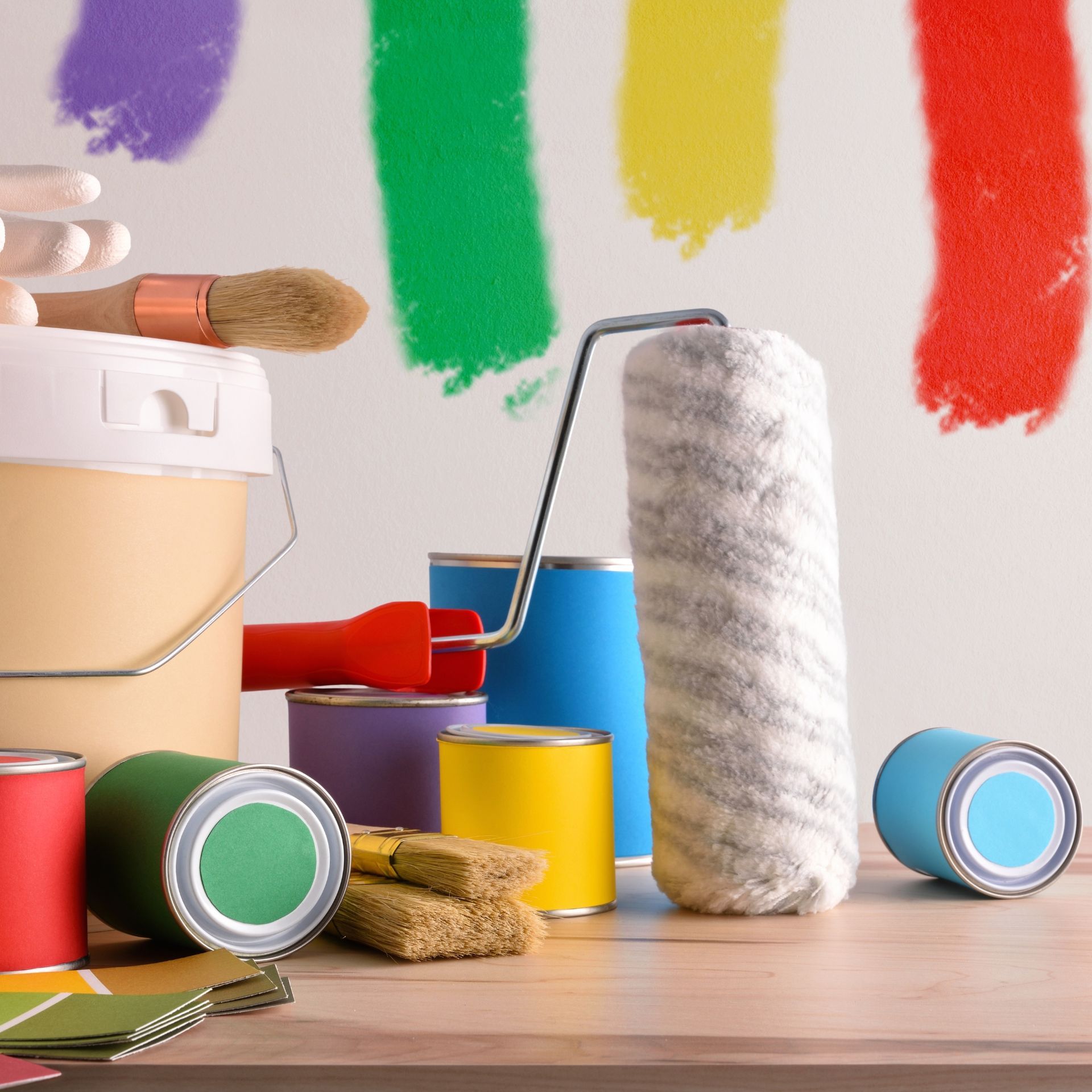 A person wearing a hat and vest uses a paint roller on an interior wall, covering a white section with orange paint.