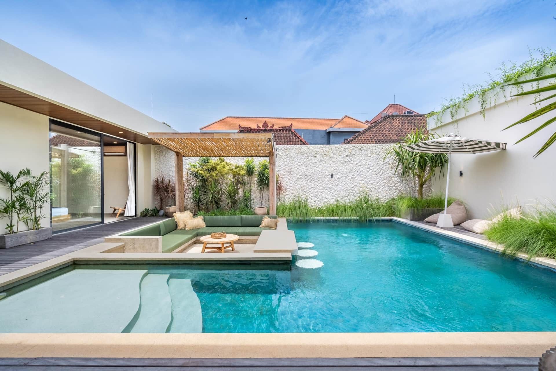 Poolside lounge area with a pool, seating area, and lush greenery.