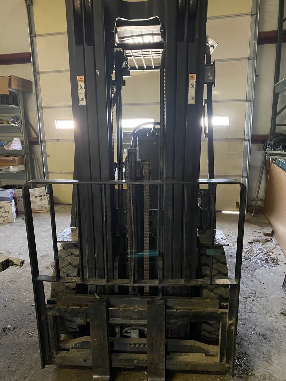 A forklift is parked in front of a garage door