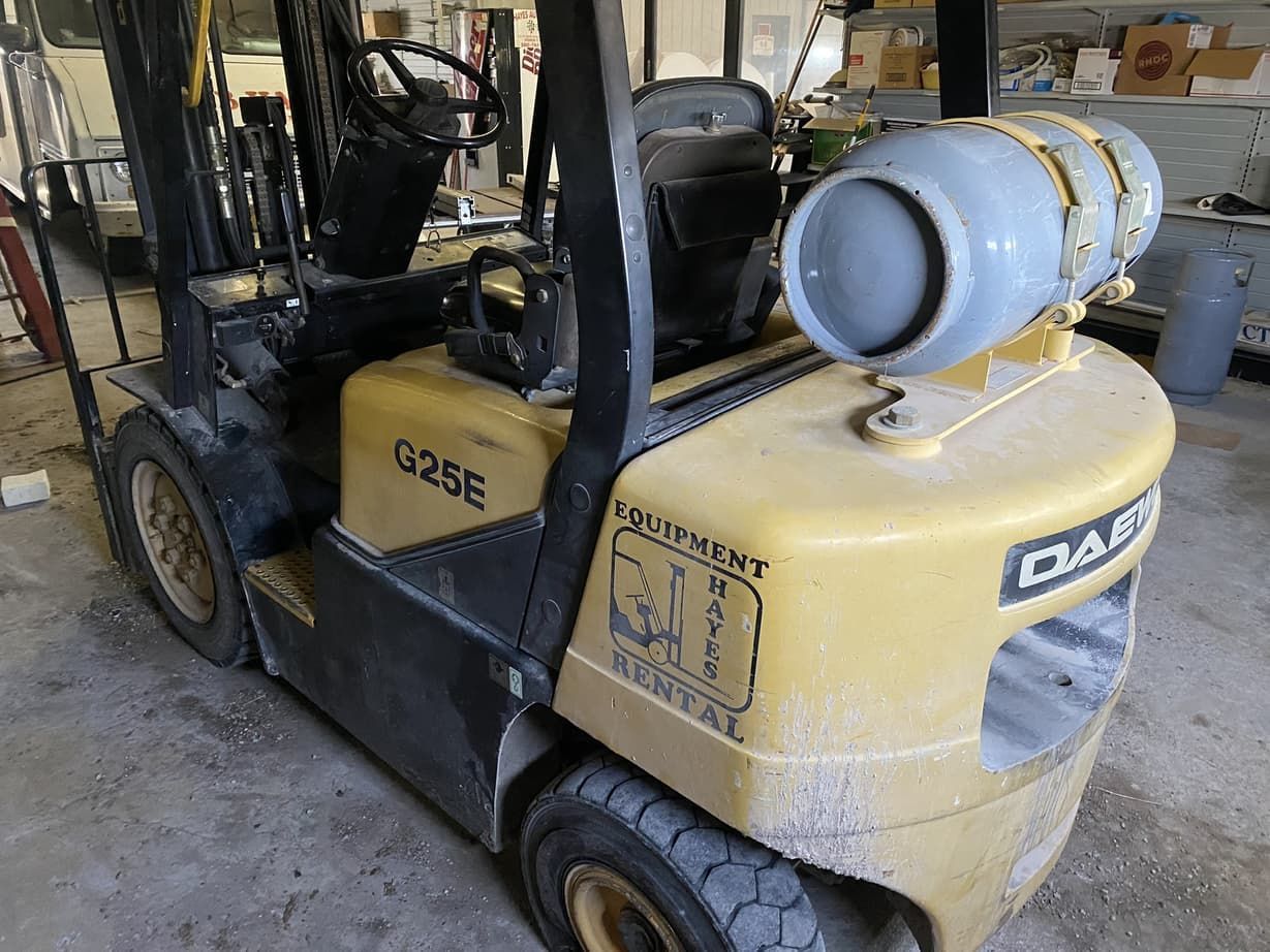 A forklift with a propane tank on top of it is parked in a garage.